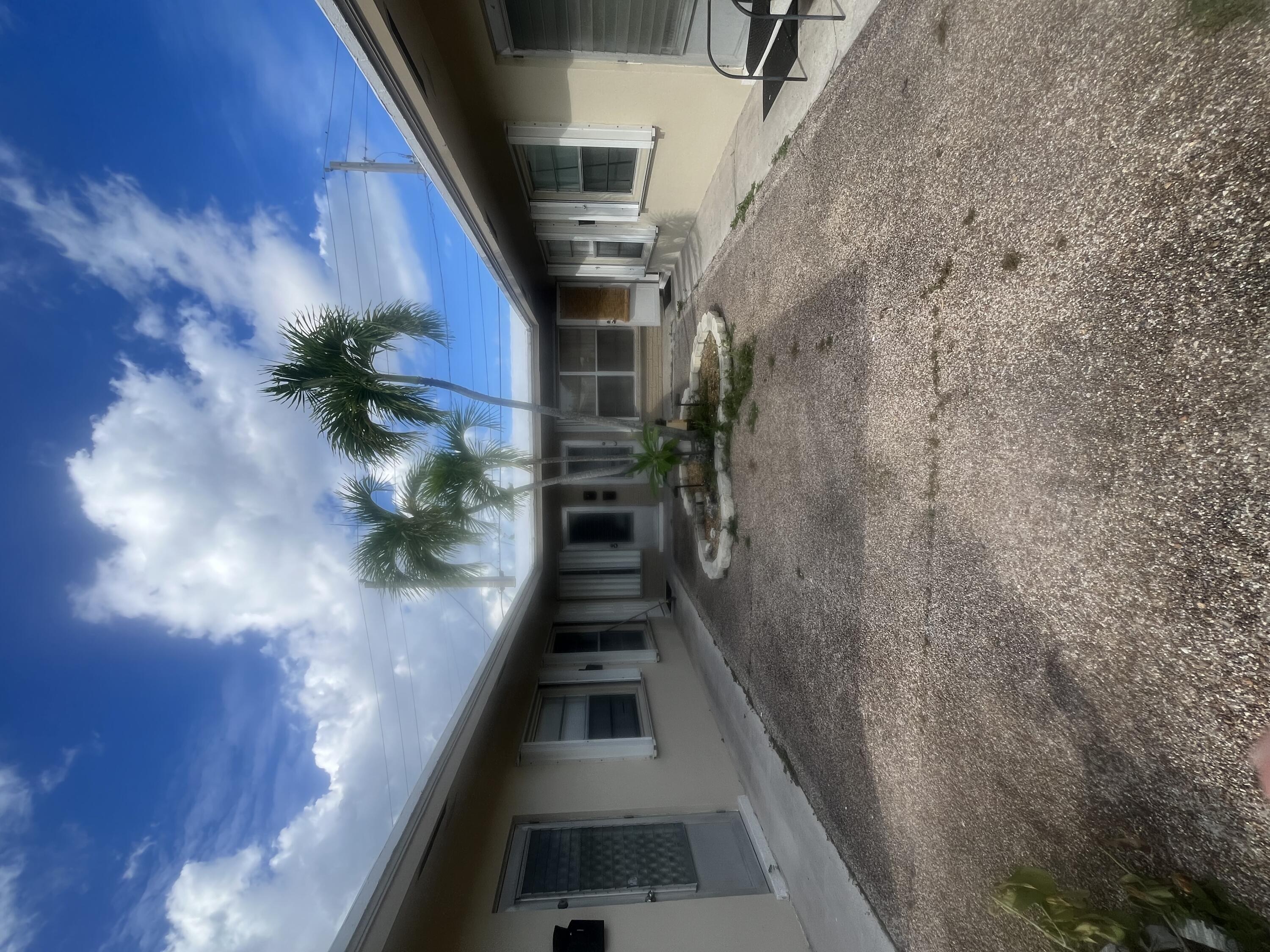 1017 Southeast 3rd Street, Unit 5 Deerfield Beach, FL 33441 - Photo 1 of 16 a view of a patio with table and chairs under an umbrella with large trees