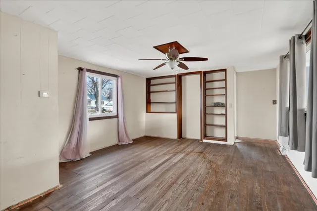 an empty room with wooden floor closet and windows