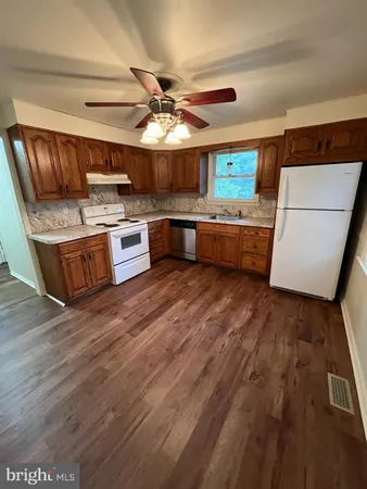 a large kitchen with stainless steel appliances granite countertop a lot of counter space and wooden floor