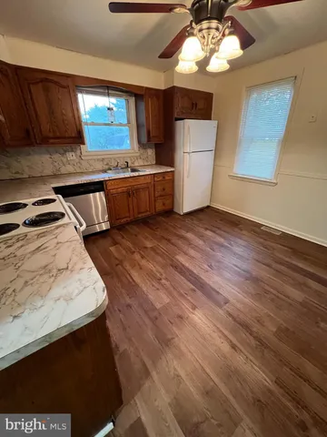 a kitchen with stainless steel appliances wooden floors wooden cabinets a sink and a stove