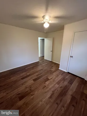 wooden floor in an empty room with a chandelier fan