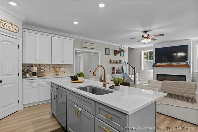 a kitchen with a sink dishwasher a stove and white cabinets with wooden floor