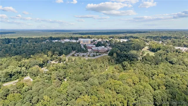 an aerial view of residential house with outdoor space and trees all around