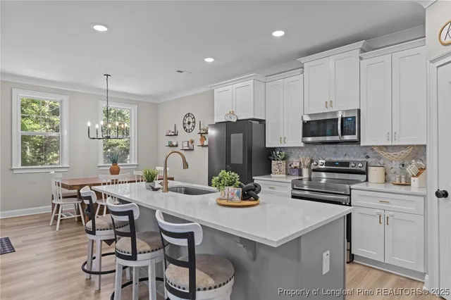 a kitchen with stainless steel appliances a white table chairs and a refrigerator