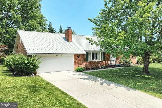 a front view of a house with a garden and tree