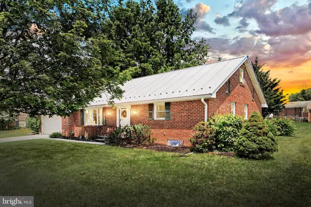 a backyard of a house with table and chairs plants and large tree