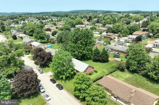 an aerial view of residential houses with outdoor space and trees all around