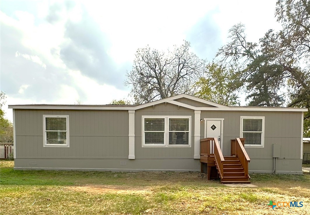 a front view of a house with a garden and lake view