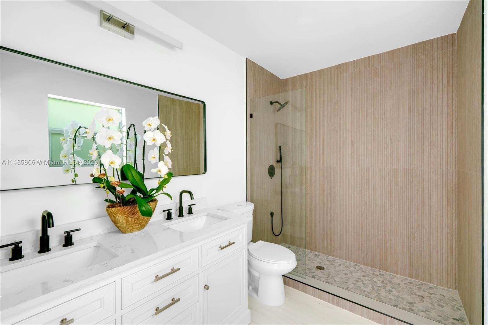 2385 North Bay Road Miami Beach, FL 33140 - Photo 16 of 36 a bathroom with a sink a mirror a toilet and shower