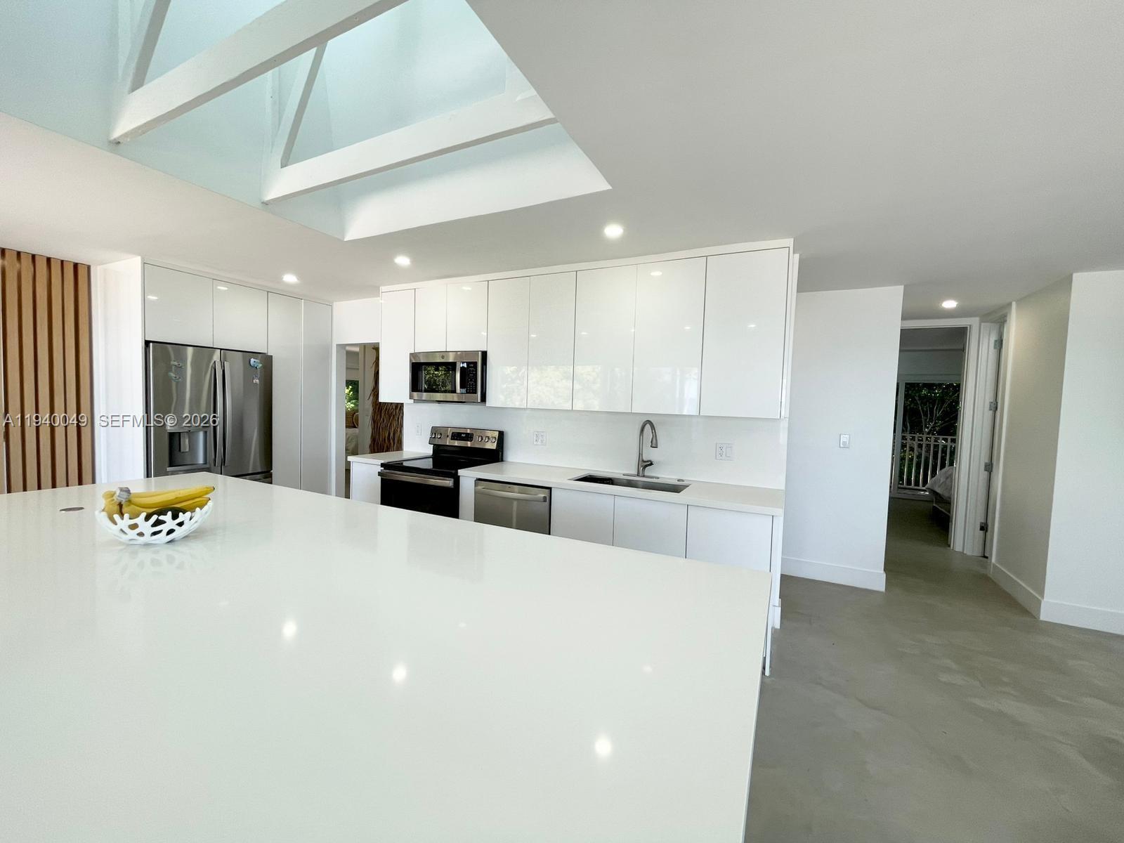 96180 Overseas Highway, Unit 1 Key Largo, FL 33037 - Photo 65 of 83 a large white kitchen with stainless steel appliances kitchen island a stove a refrigerator a sink a lots of counter top space and cabinets