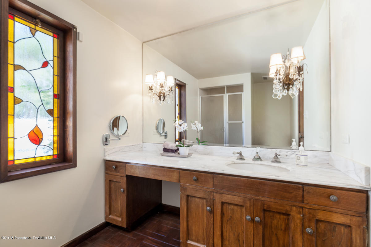 700 South Orange Grove Boulevard Pasadena, CA 91105 - Photo 29 of 50 a bathroom with a granite countertop sink a large mirror and a window