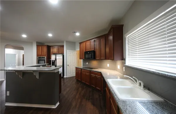a kitchen with stainless steel appliances granite countertop sink stove top oven and cabinets