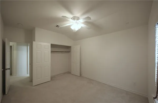 an empty room with closet and a chandelier fan