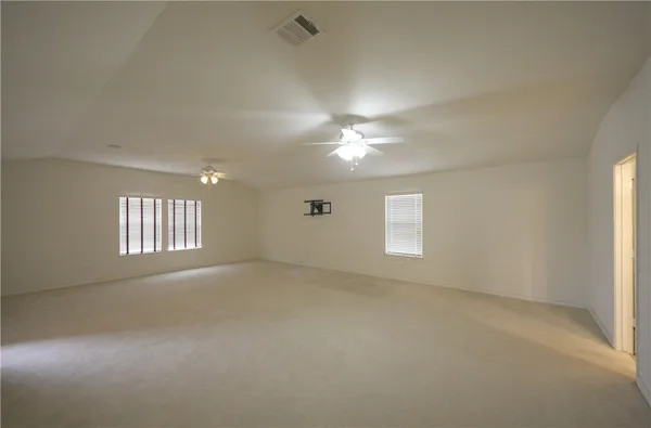 an empty room with windows and chandelier fan