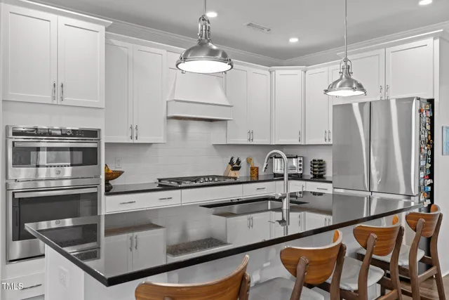 a kitchen with stainless steel appliances granite countertop a sink a stove a refrigerator and cabinets