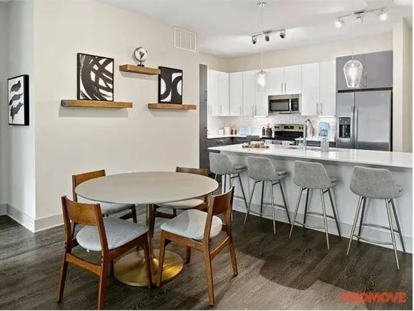 a view of kitchen with stainless steel appliances refrigerator stove dining table and chairs