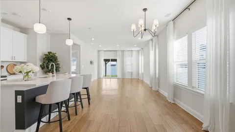a view of a dining room and livingroom with furniture wooden floor a chandelier