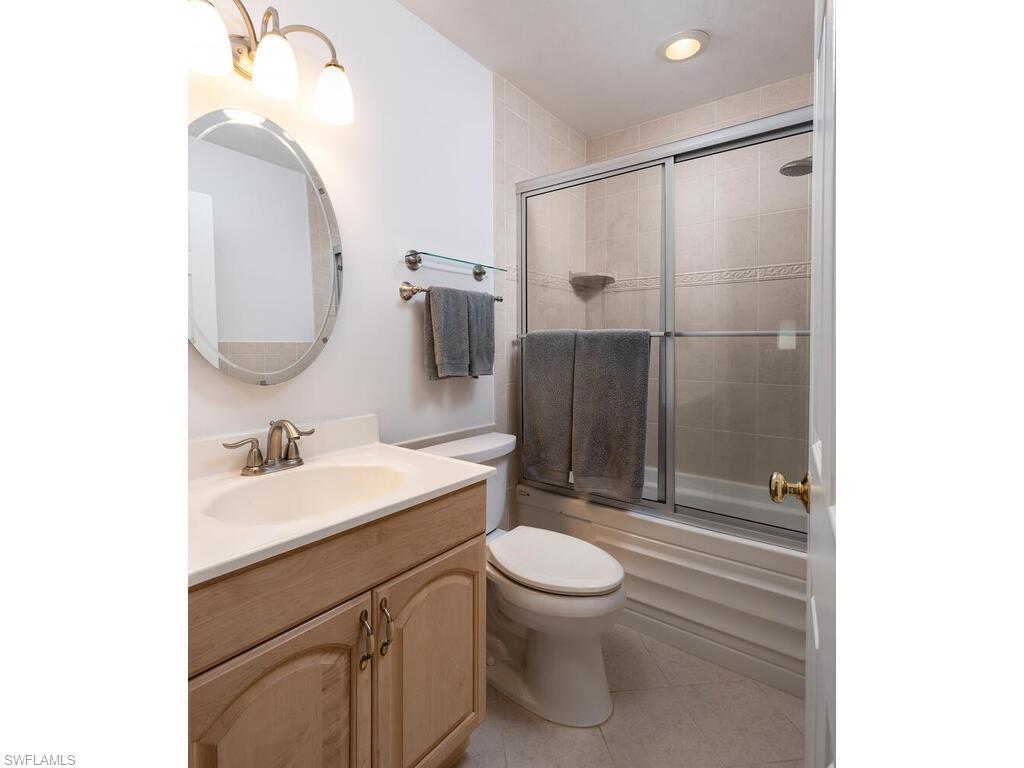 1036 Lake Shore Court Naples, FL 34103 - Photo 10 of 15 Full bath with tile patterned flooring, toilet, vanity, and bath / shower combo with glass door