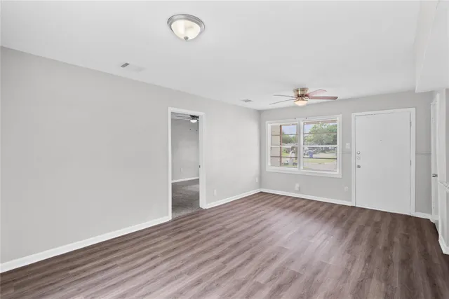an empty room with wooden floor and windows