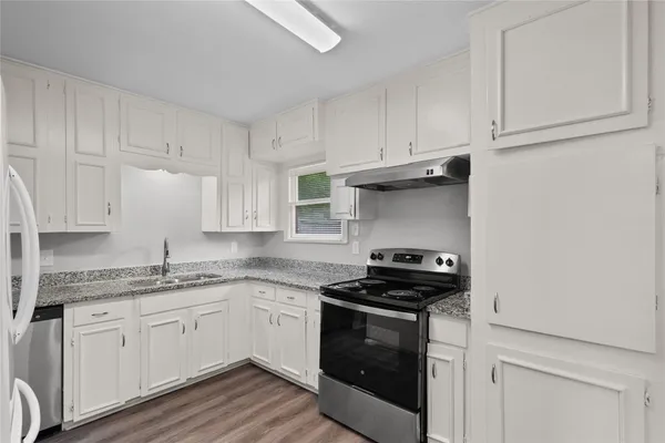a kitchen with granite countertop white cabinets and a stove
