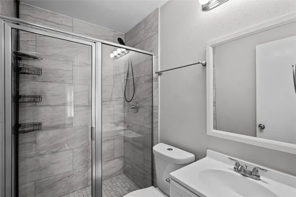 a bathroom with a shower sink vanity and toilet