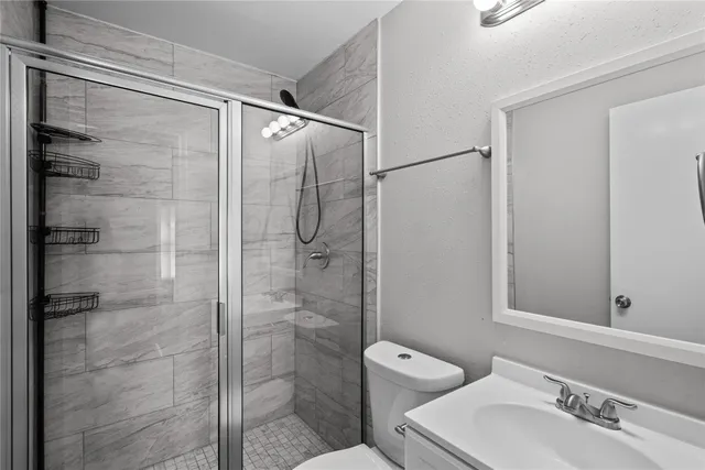 a bathroom with a shower sink vanity and toilet