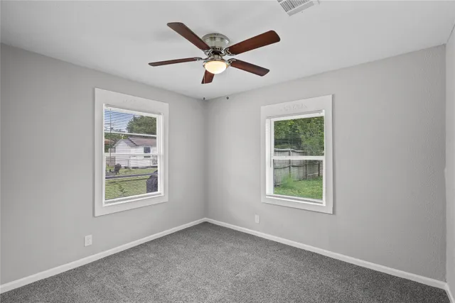 an empty room with windows and ceiling fan