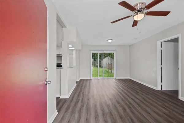 a view of a big room with wooden floor a ceiling fan and windows