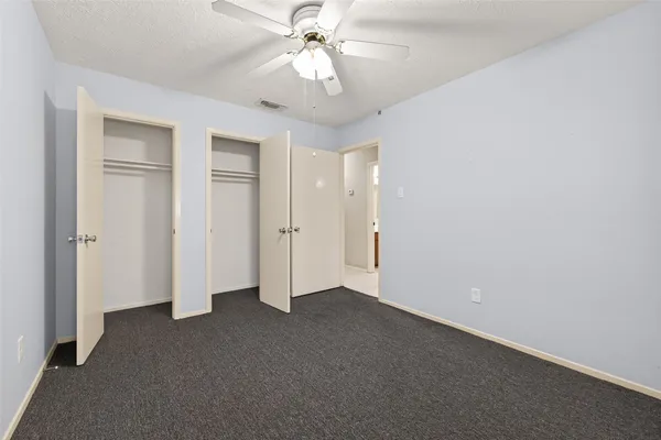 an empty room with closet and a chandelier fan
