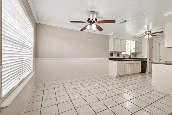 a kitchen with granite countertop a refrigerator and white cabinets
