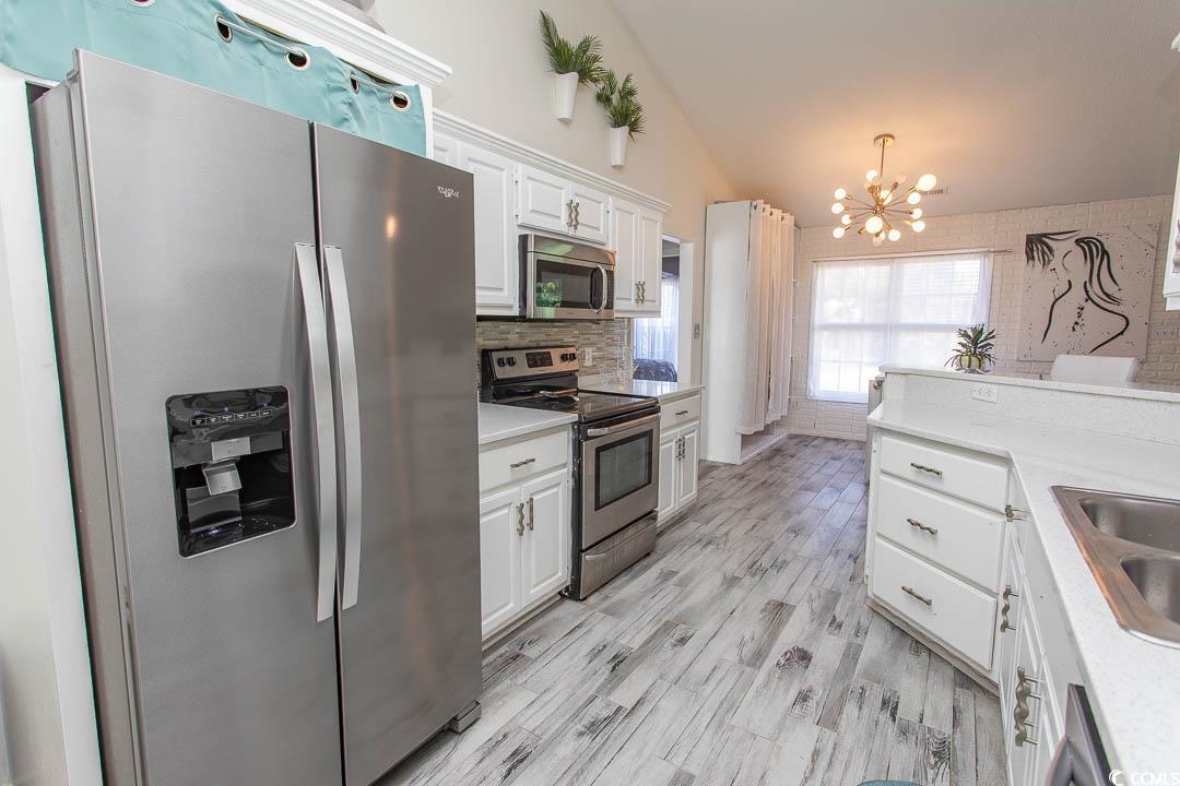 761 Drawbridge Drive Conway, SC 29526 - Photo 6 of 36 Kitchen featuring stainless steel appliances, white cabinets, vaulted ceiling, a chandelier, and light wood finished floors