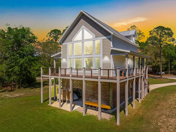 a view of house with a big yard and large trees