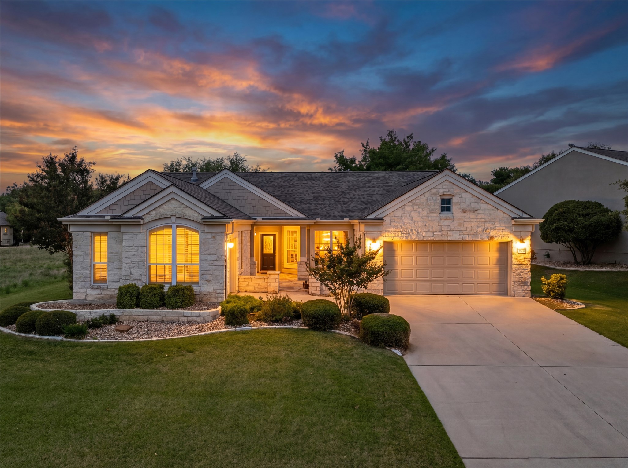 The property features a stone facade, an attached garage, and a well-maintained front lawn with established landscaping