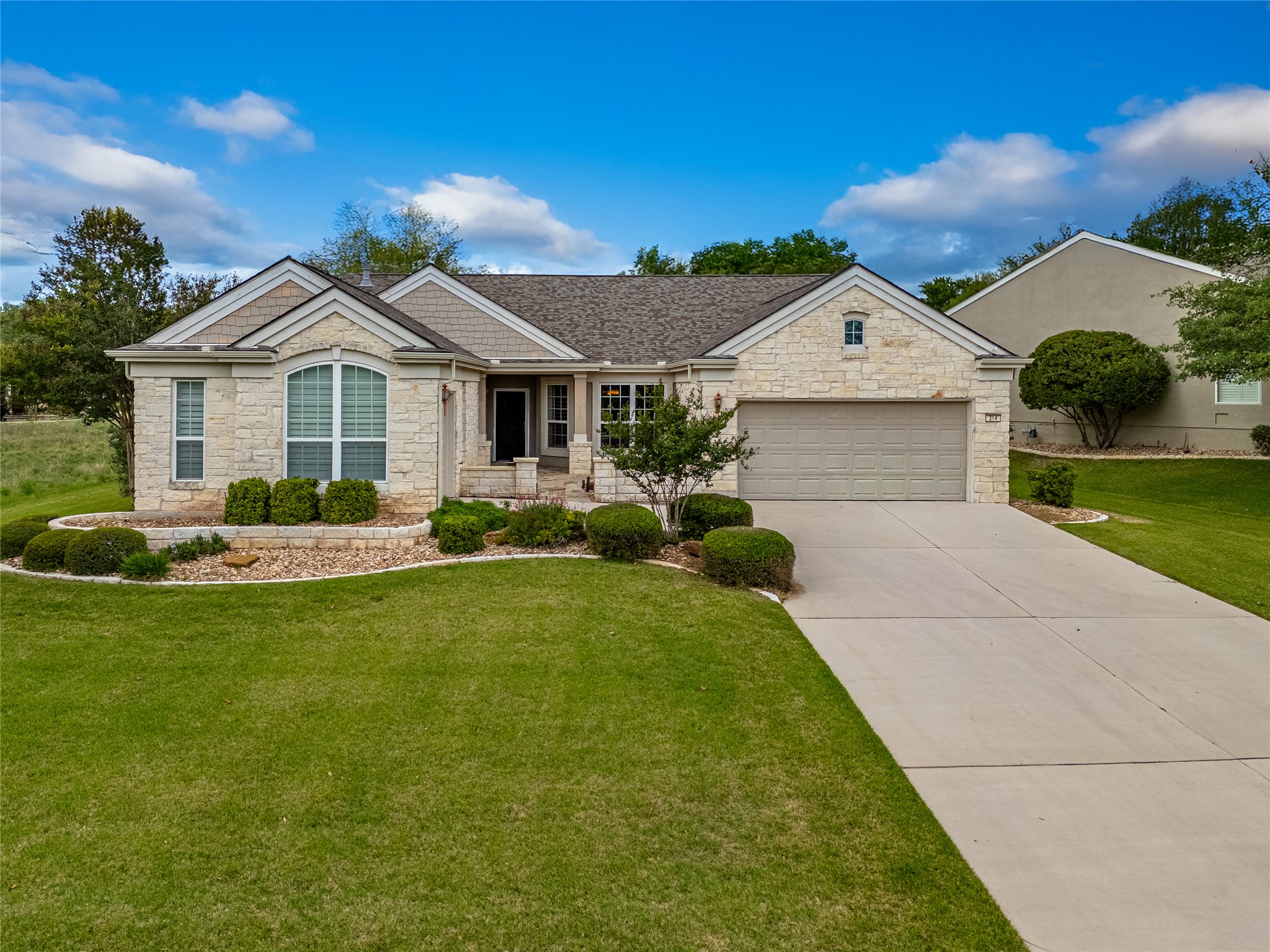 214 Summit Street Georgetown, TX 78633 - Photo 2 of 38 This property features a stone facade, an attached garage, a well-maintained lawn, and a paved driveway
