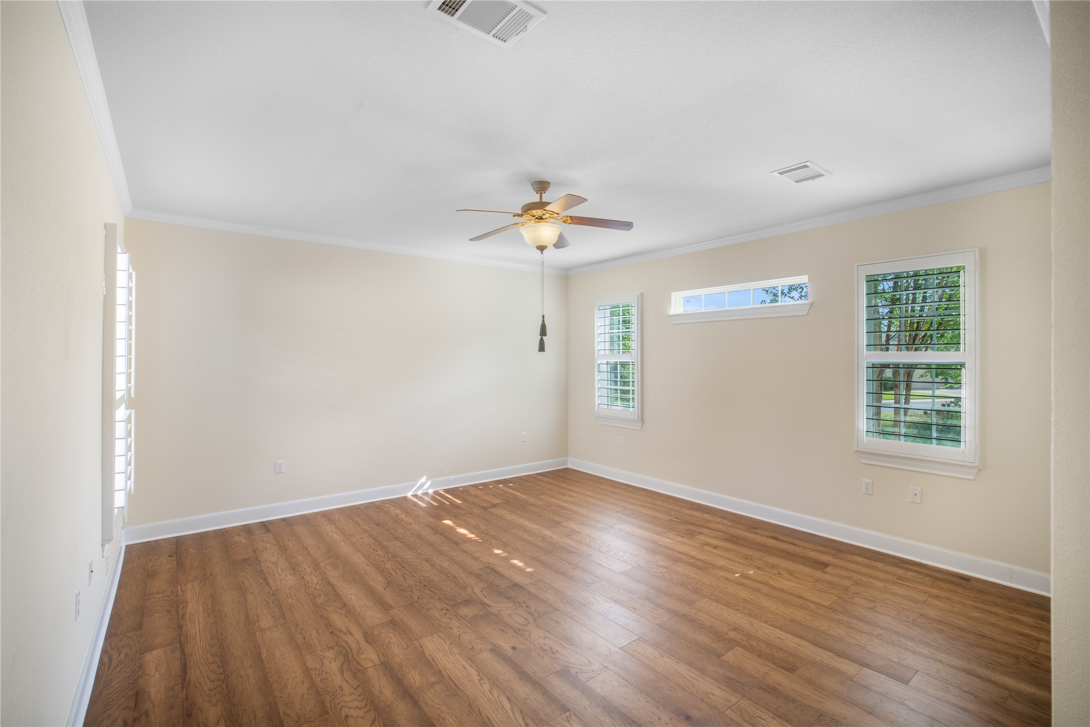 214 Summit Street Georgetown, TX 78633 - Photo 21 of 38 Spacious room featuring hardwood style flooring, crown molding, a ceiling fan with light, and windows equipped with plantation shutters