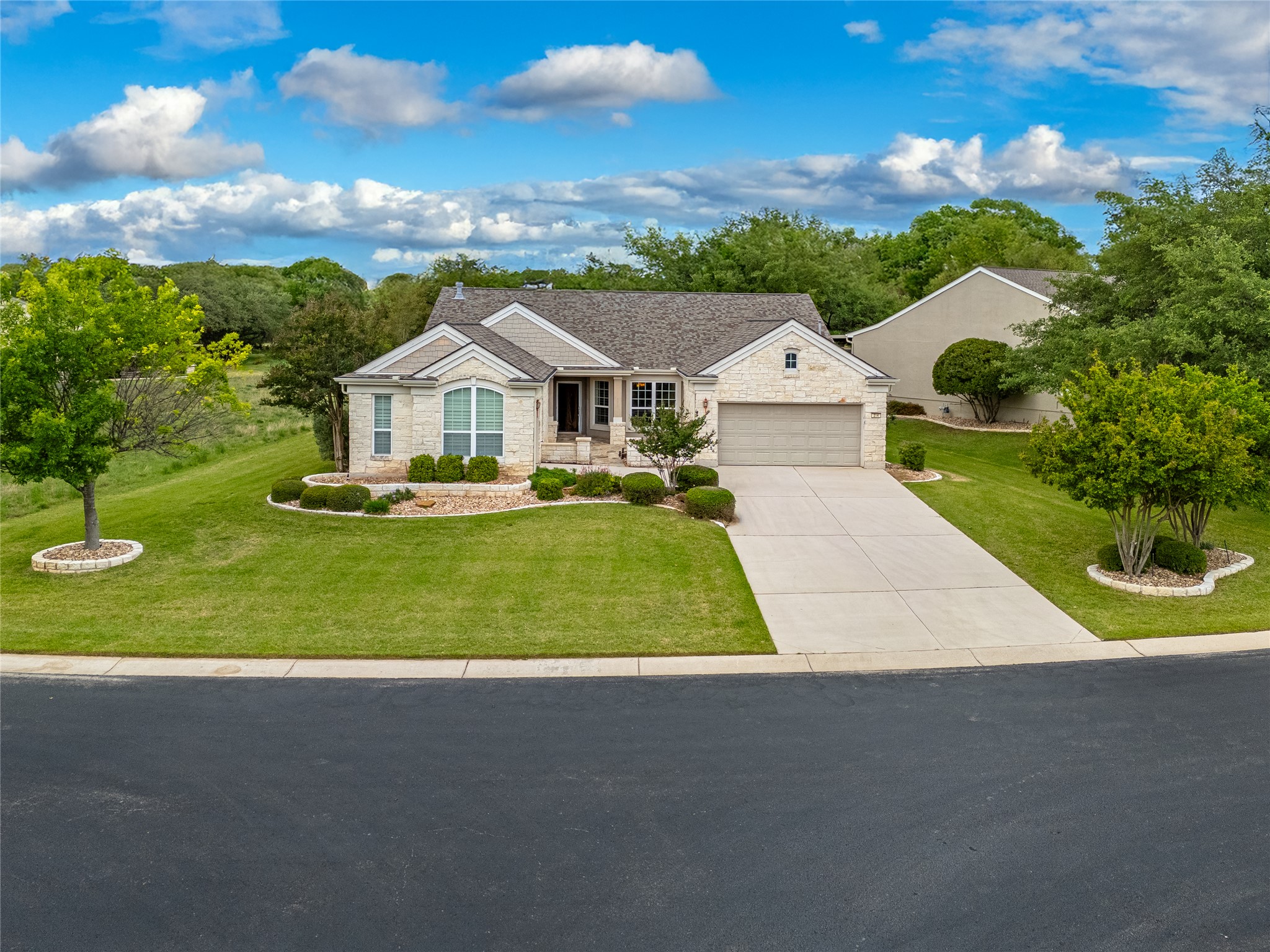 214 Summit Street Georgetown, TX 78633 - Photo 3 of 38 The property features a light-colored brick exterior, a paved driveway leading to an attached garage, and a well-maintained lawn with landscaping