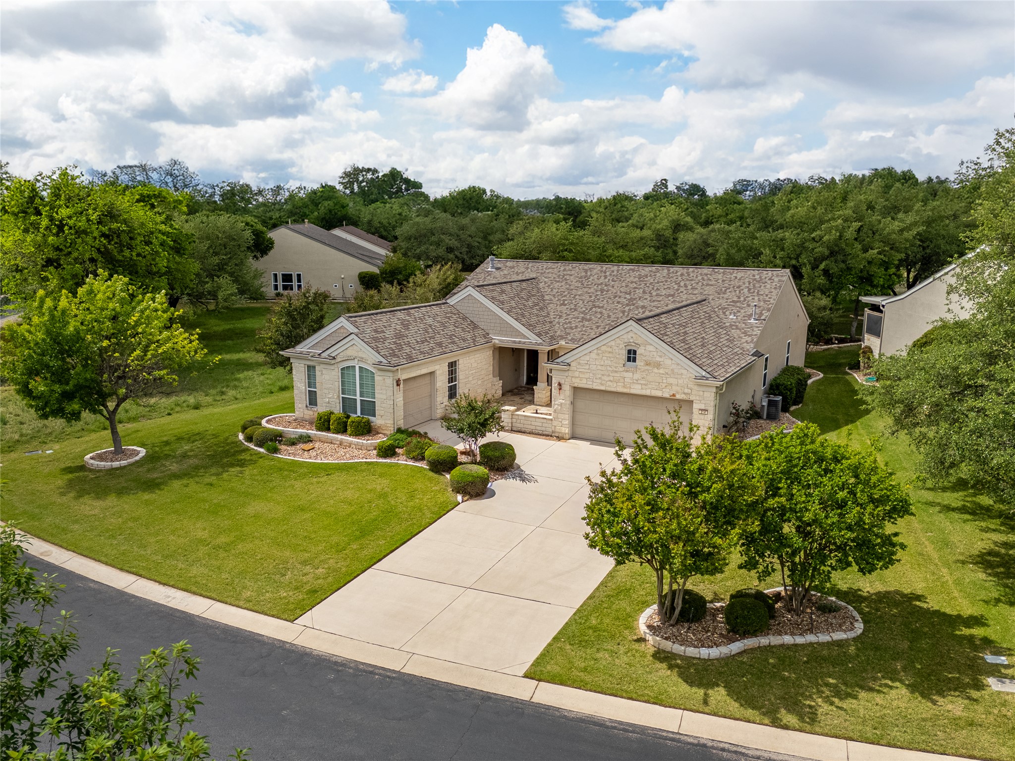 214 Summit Street Georgetown, TX 78633 - Photo 4 of 38 Exterior view of the property featuring a stone facade, an attached garage, a paved driveway, and a well-maintained lawn with landscaping
