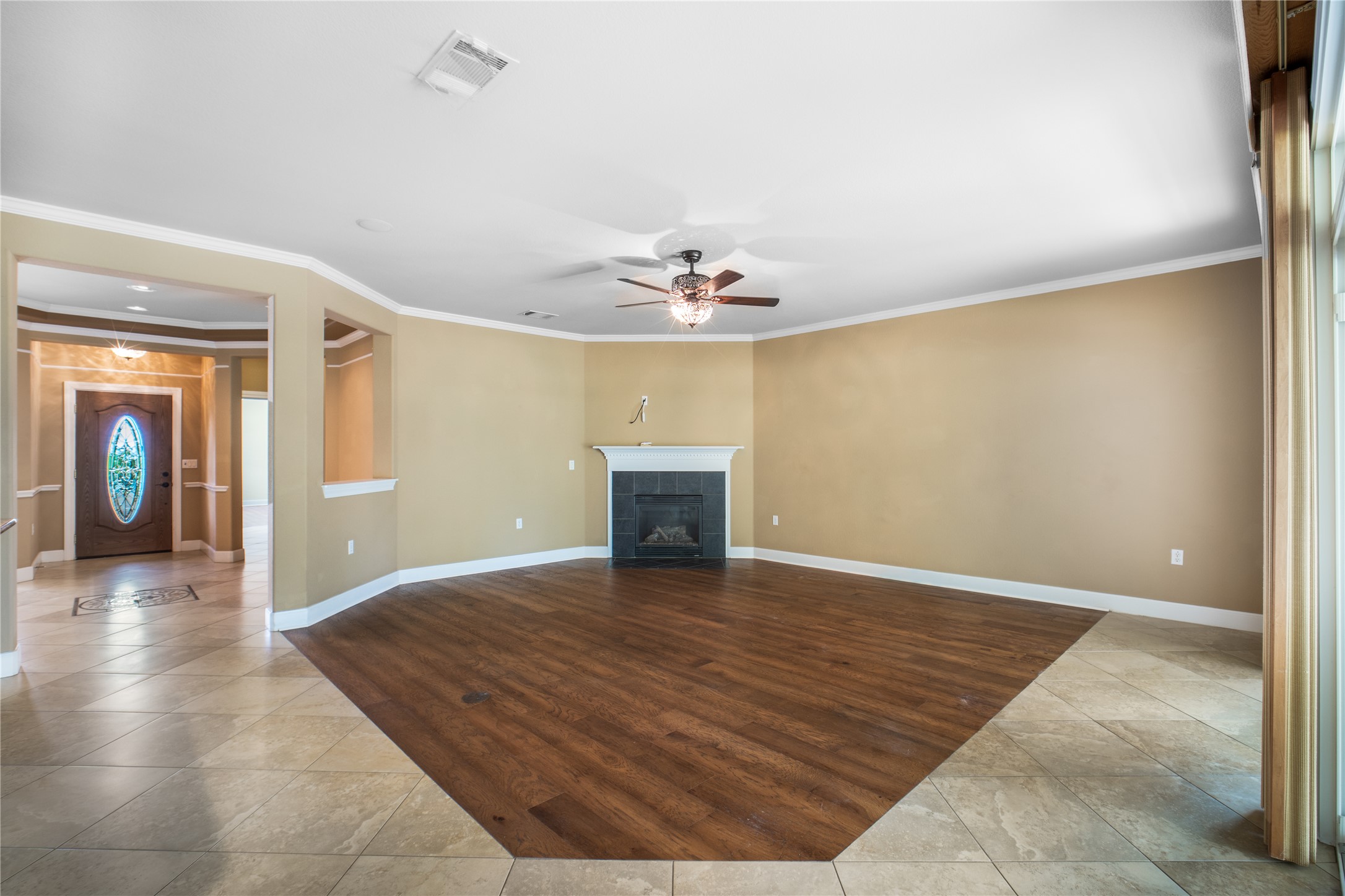 214 Summit Street Georgetown, TX 78633 - Photo 7 of 38 Inviting living space featuring a fireplace with a white mantle, an overhead ceiling fan, and varied flooring with wood and tile sections