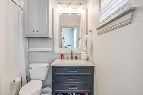 a bathroom with a toilet sink vanity and mirror