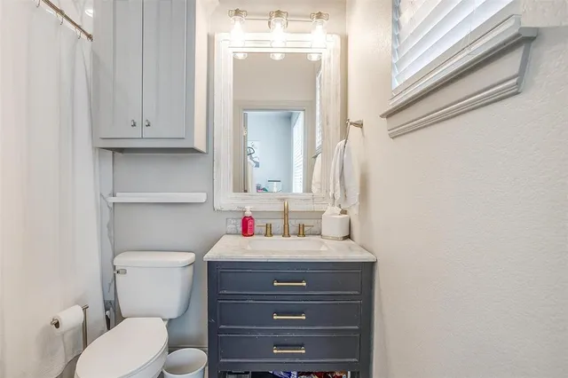 a bathroom with a toilet sink vanity and mirror
