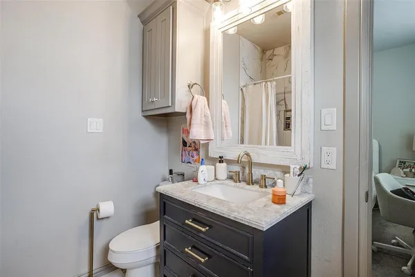 a bathroom with a granite countertop toilet sink and mirror