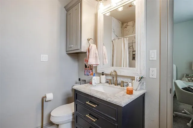 a bathroom with a granite countertop toilet sink and mirror