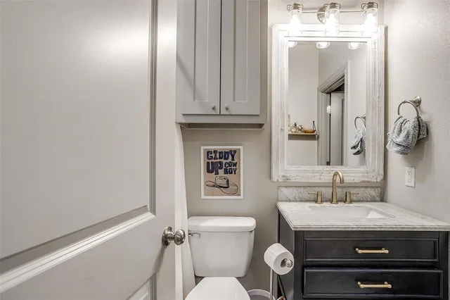 a bathroom with a granite countertop toilet a sink and a mirror