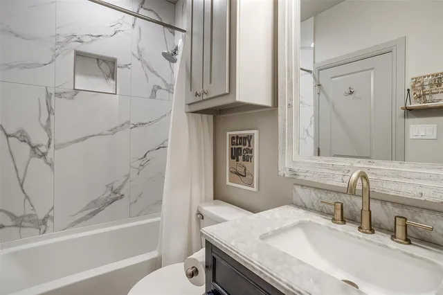 a bathroom with a granite countertop sink a toilet and bathtub