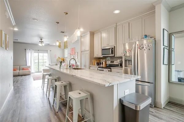 a kitchen with stainless steel appliances a refrigerator a sink dishwasher a stove and a dining table with wooden floor
