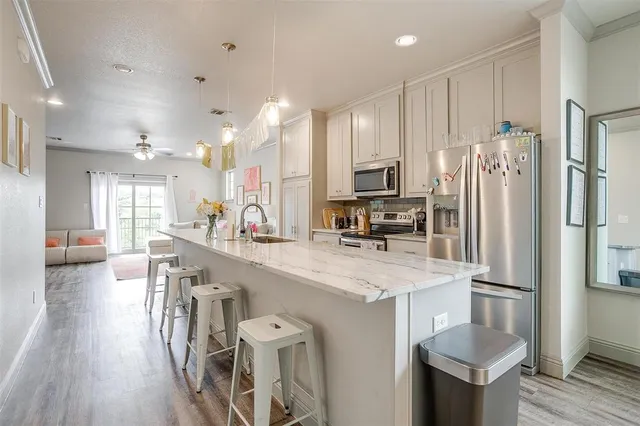 a kitchen with stainless steel appliances a refrigerator a sink dishwasher a stove and a dining table with wooden floor