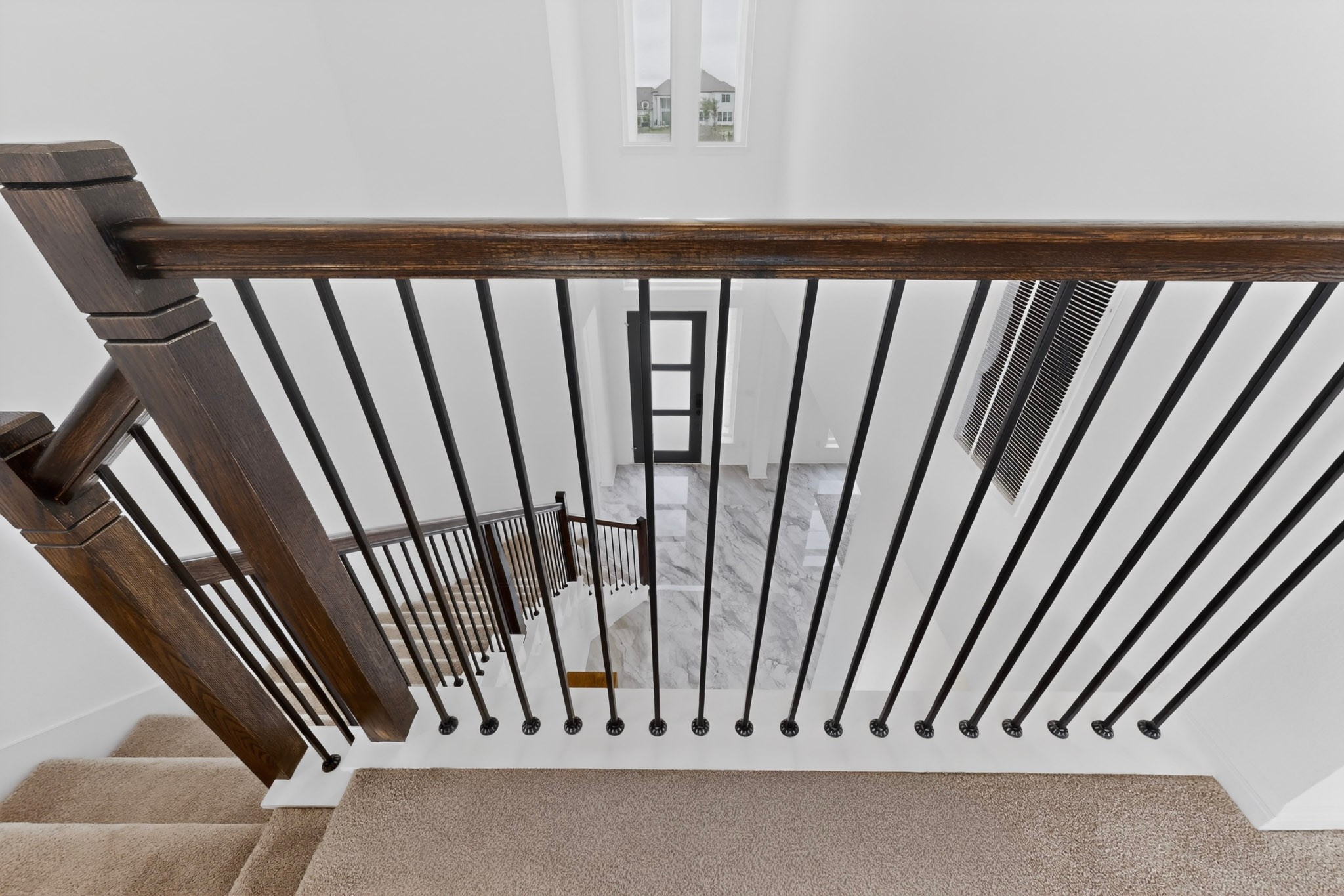 2308 Mondello Path Leander, TX 78641 - Photo 22 of 39 A grand, multi-level entryway with a dark wood banister and modern iron balusters.