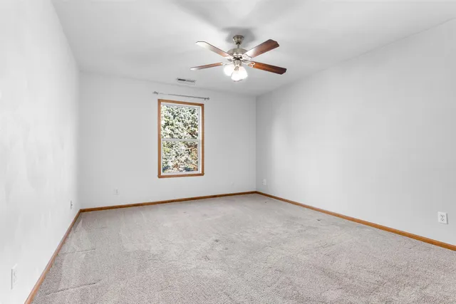 an empty room with a window and a fan