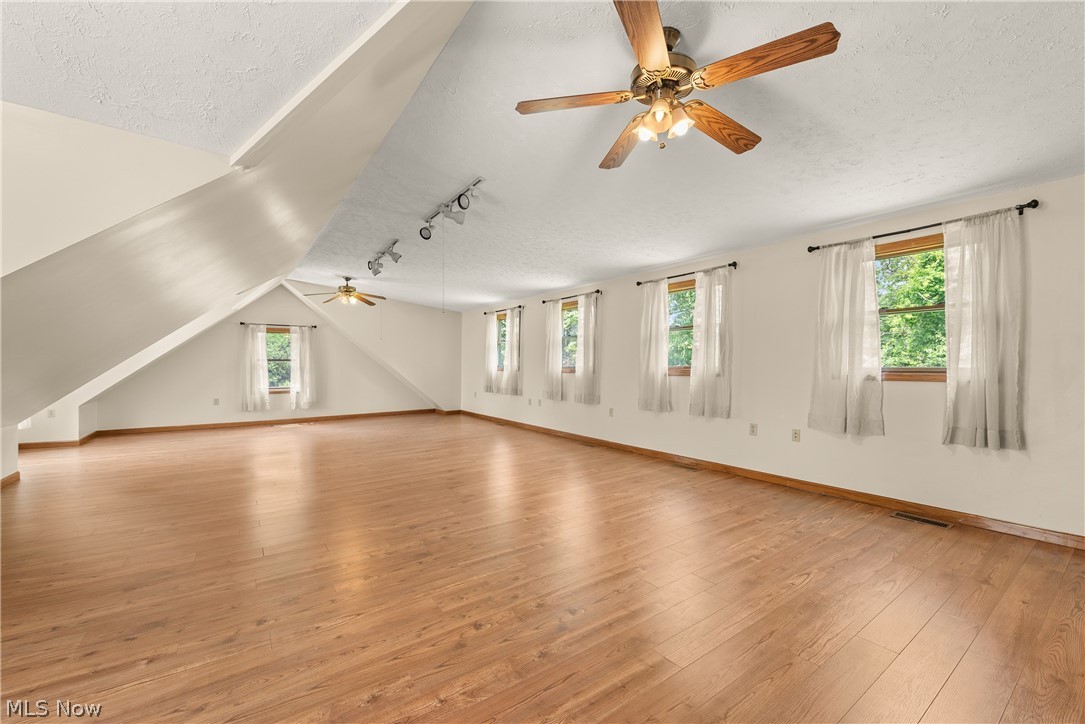 9990 Broadview Road Broadview Heights, OH 44147 - Photo 37 of 47 Unfurnished living room featuring a textured ceiling, a ceiling fan, light wood-type flooring, healthy amount of natural light, and lofted ceiling