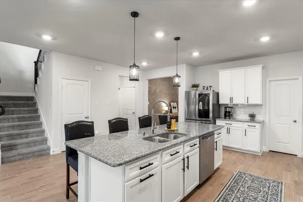 a kitchen with granite countertop white cabinets and stainless steel appliances